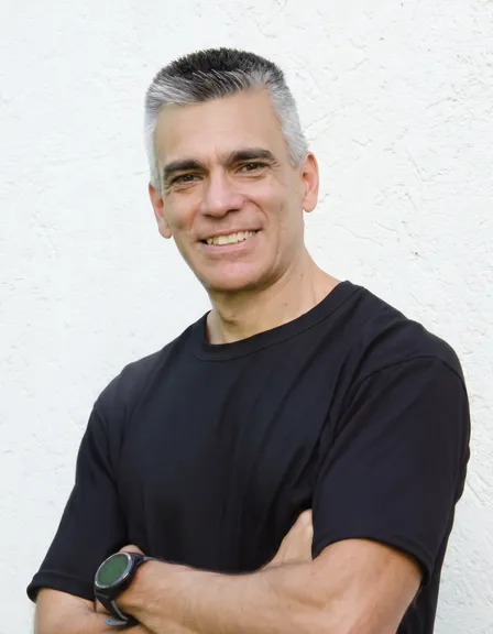 Retrato de Mg. Mauricio Moyano, de brazos cruzados y sonriendo