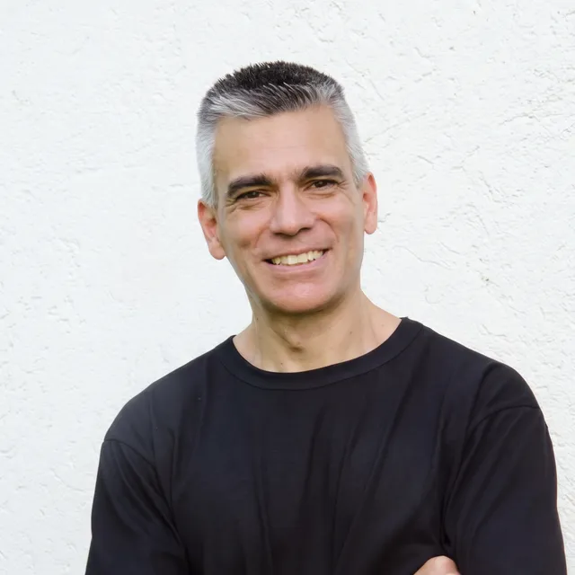 Retrato de Mg. Mauricio Moyano, de brazos cruzados y sonriendo